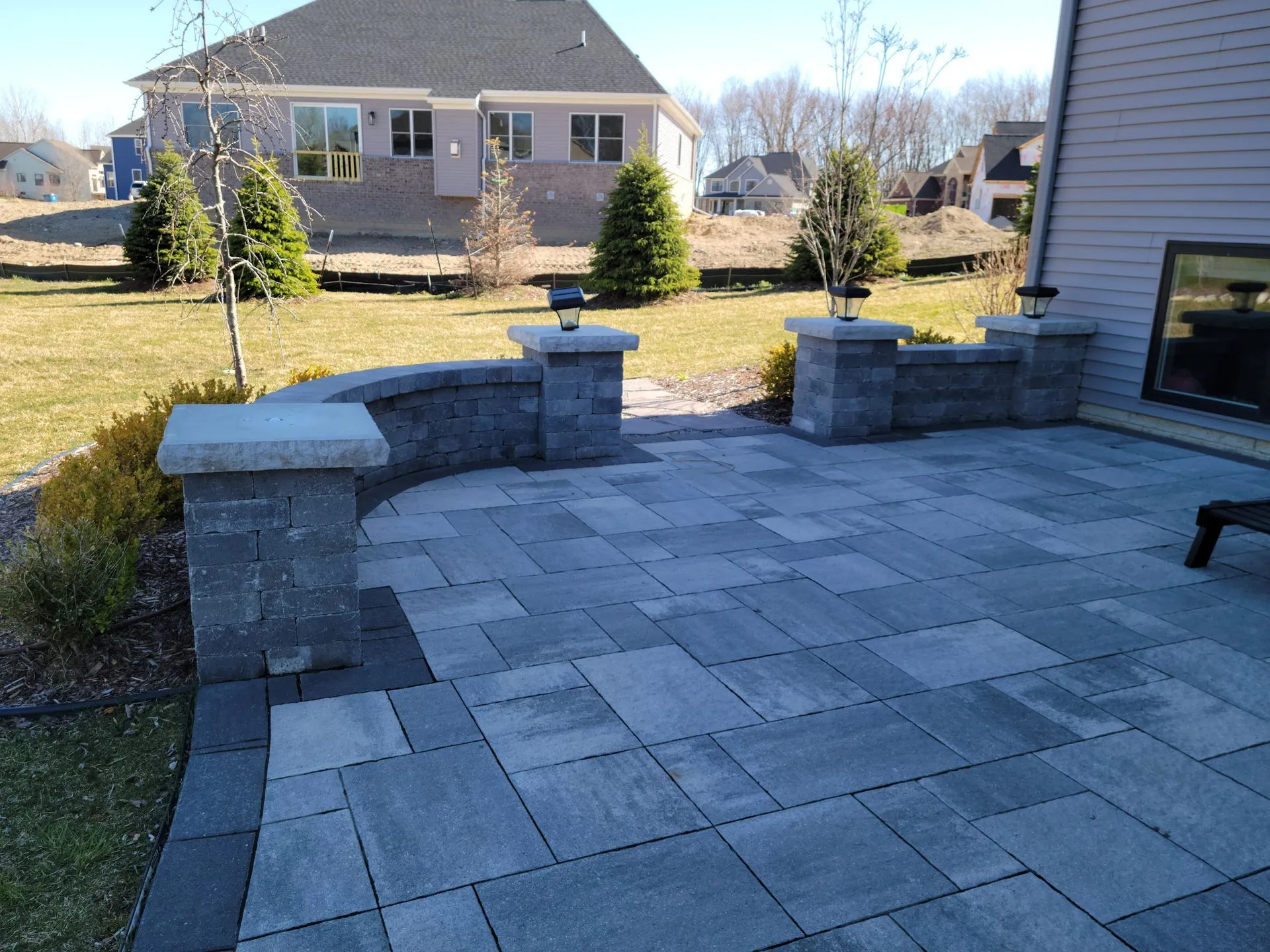 Paver walkway and hardscape bordering a residential landscape