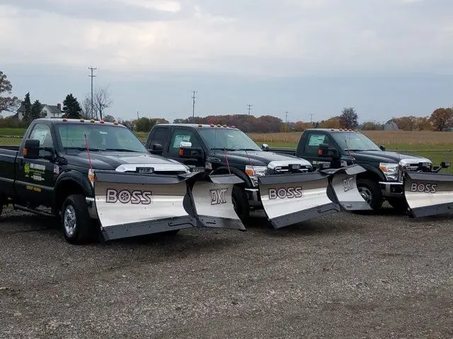 Row of KBK Landscaping trucks fitted with BOSS snow plows