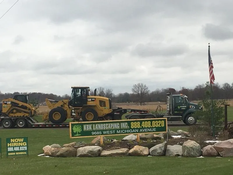 KBK Landscaping truck and loader with the company sign in front of the yard